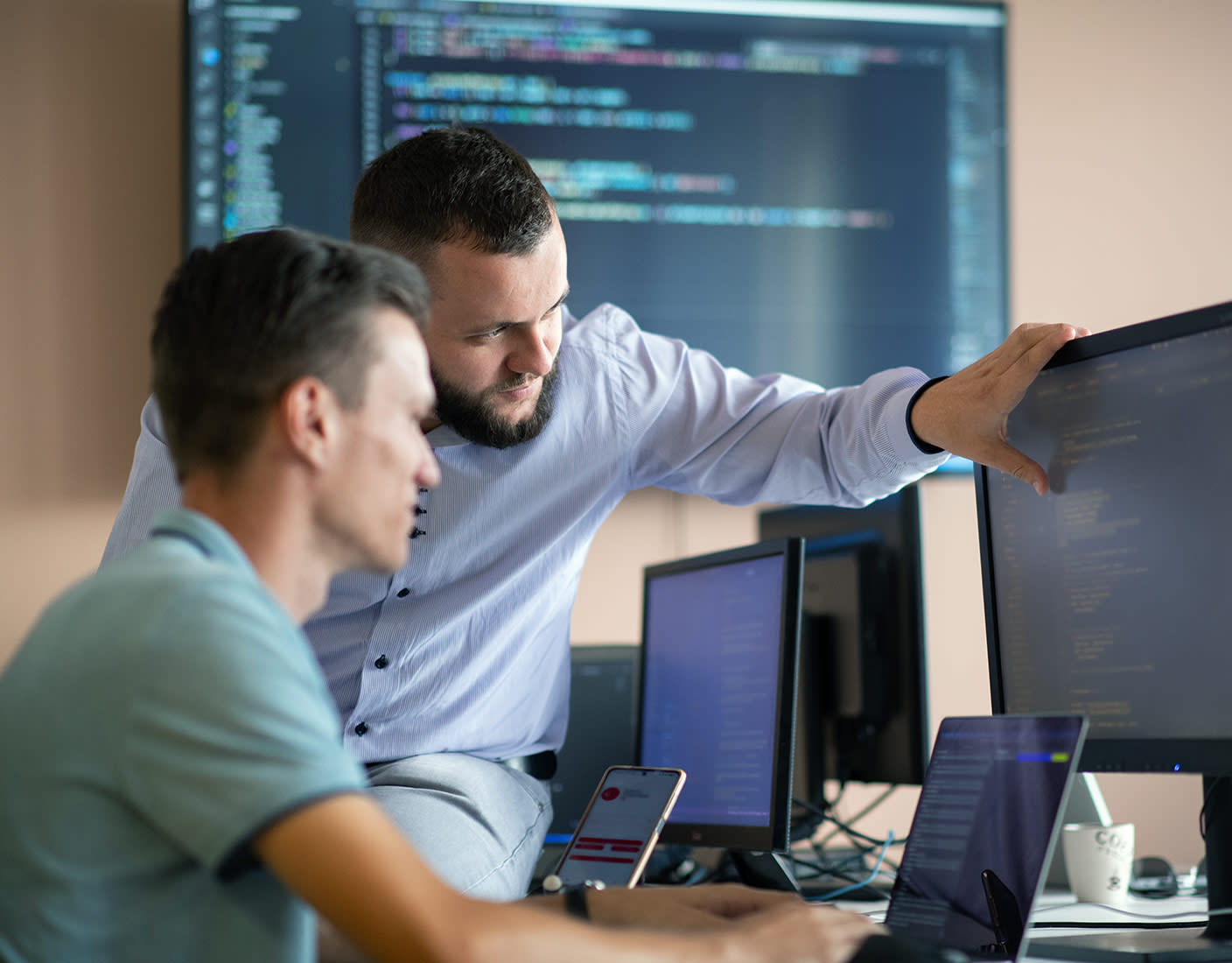 Two men collaborate on a computer, leveraging Qlik's no-code portal for real-time analytics and decision-making.